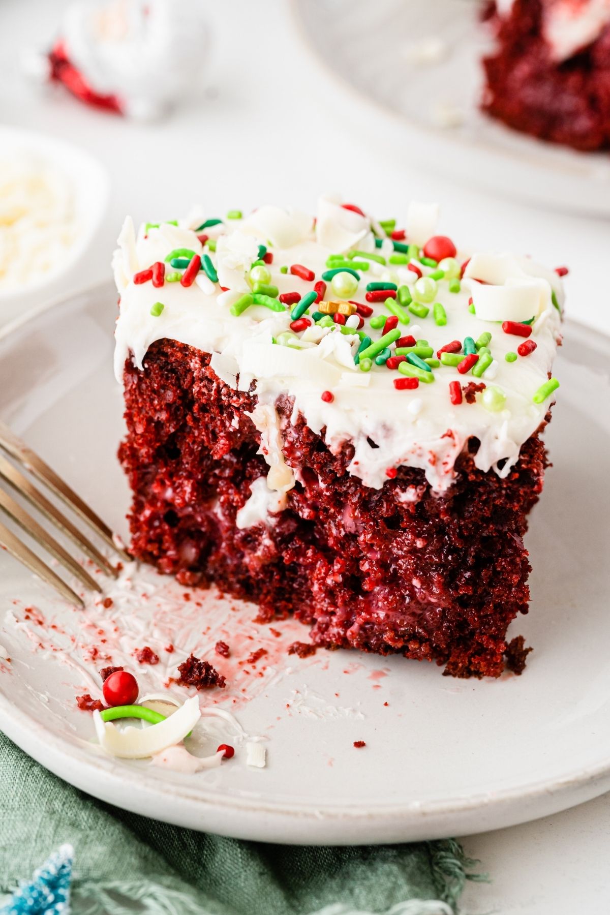 slice of red velvet poke cake with white cream in middle and white cream cheese frosting