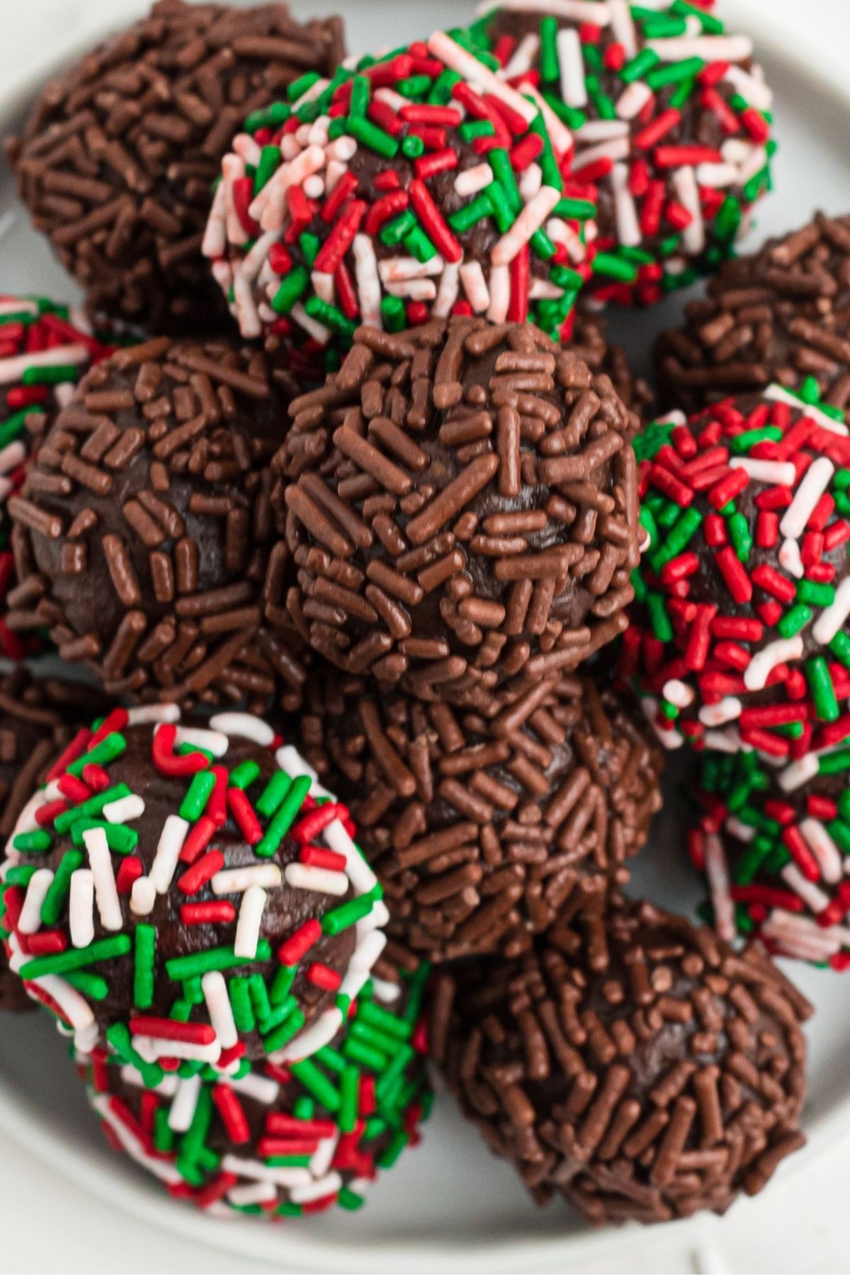 chocolate rum balls with chocolate sprinkles and a few with red, green, and white sprinkles