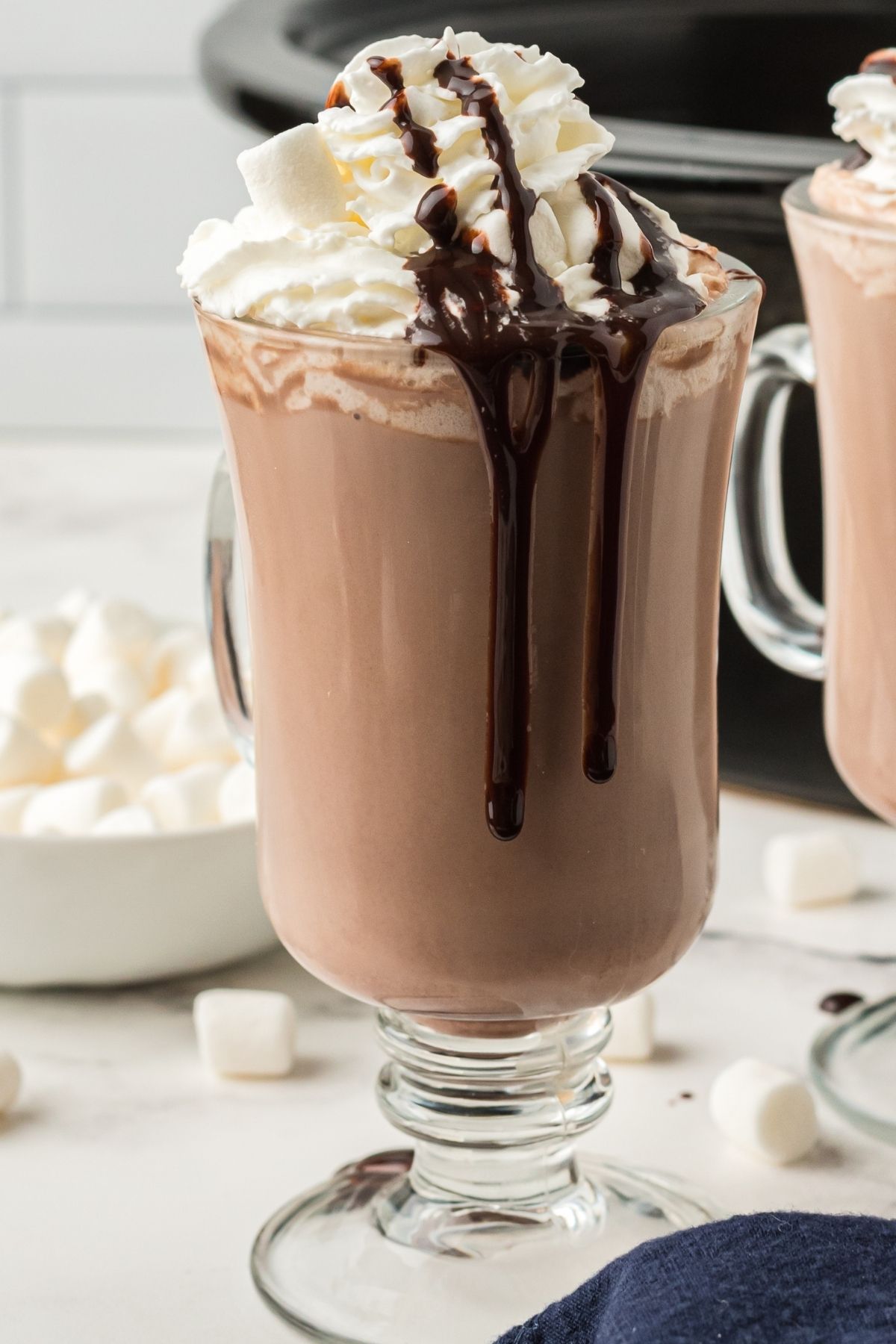 mug with hot chocolate, whipped cream, and hot chocolate sauce dripping down the side