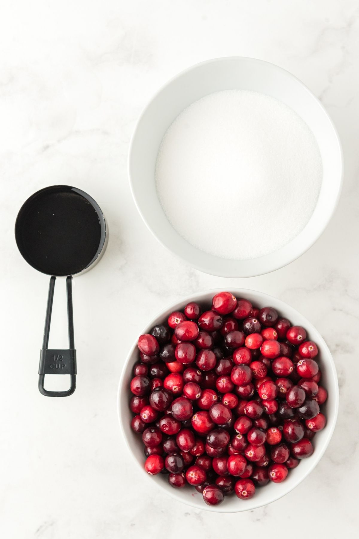 ingredients on white counter: sugar, water, fresh cranberries
