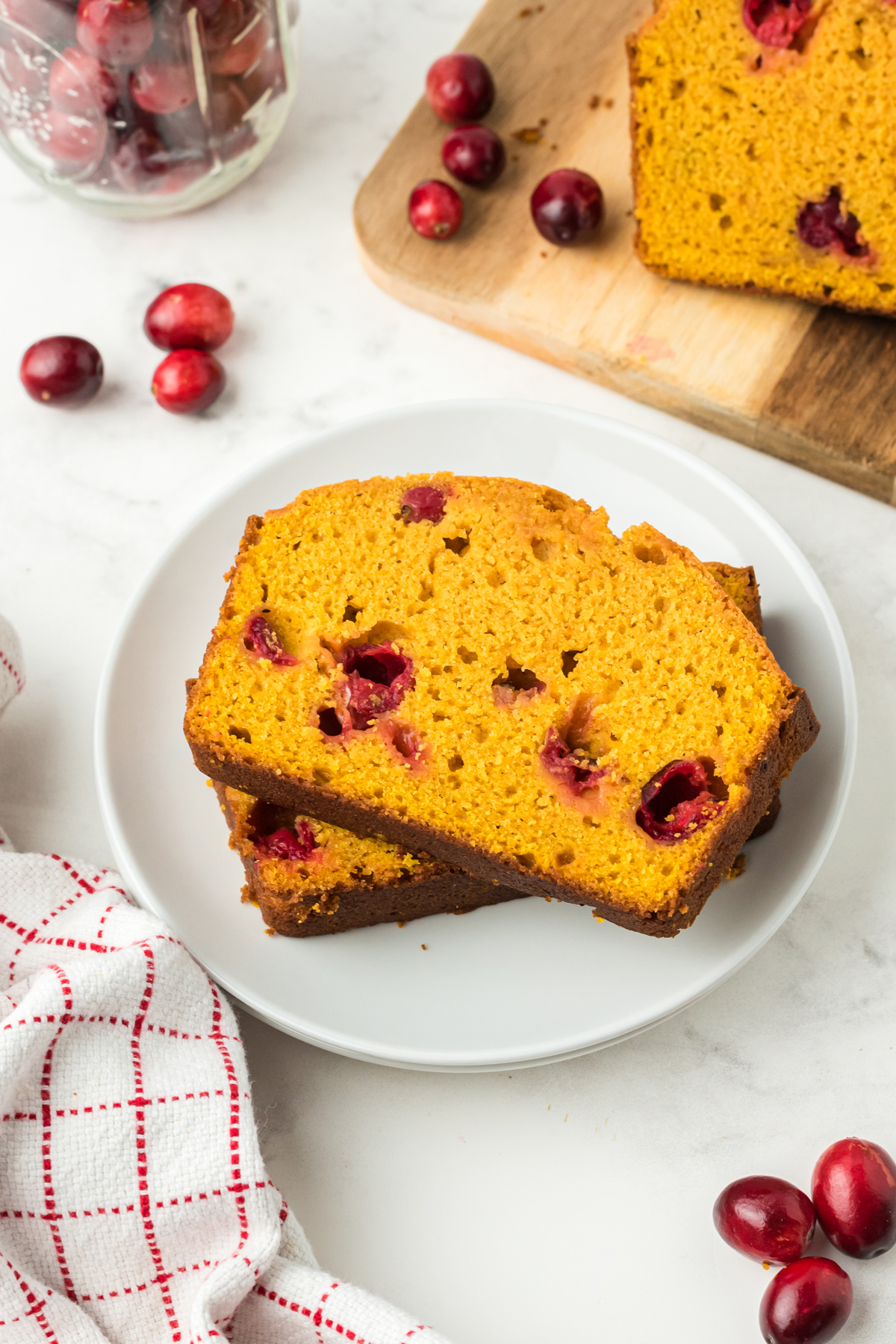 Two slices of Pumpkin Cranberry Bread on a white serving dish. 