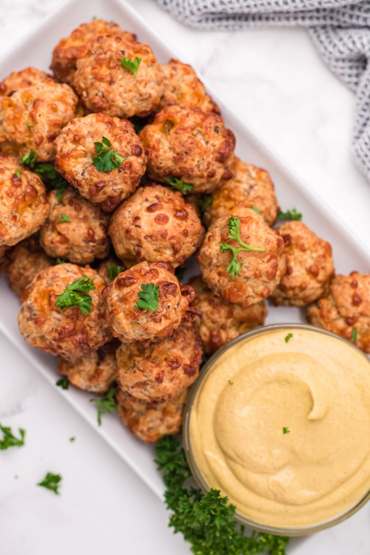 sausage balls on white plate with parsley and mustard sauce