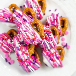 small pretzels with caramel and white chocolate with purple and pink drizzled chocolate and sprinkles