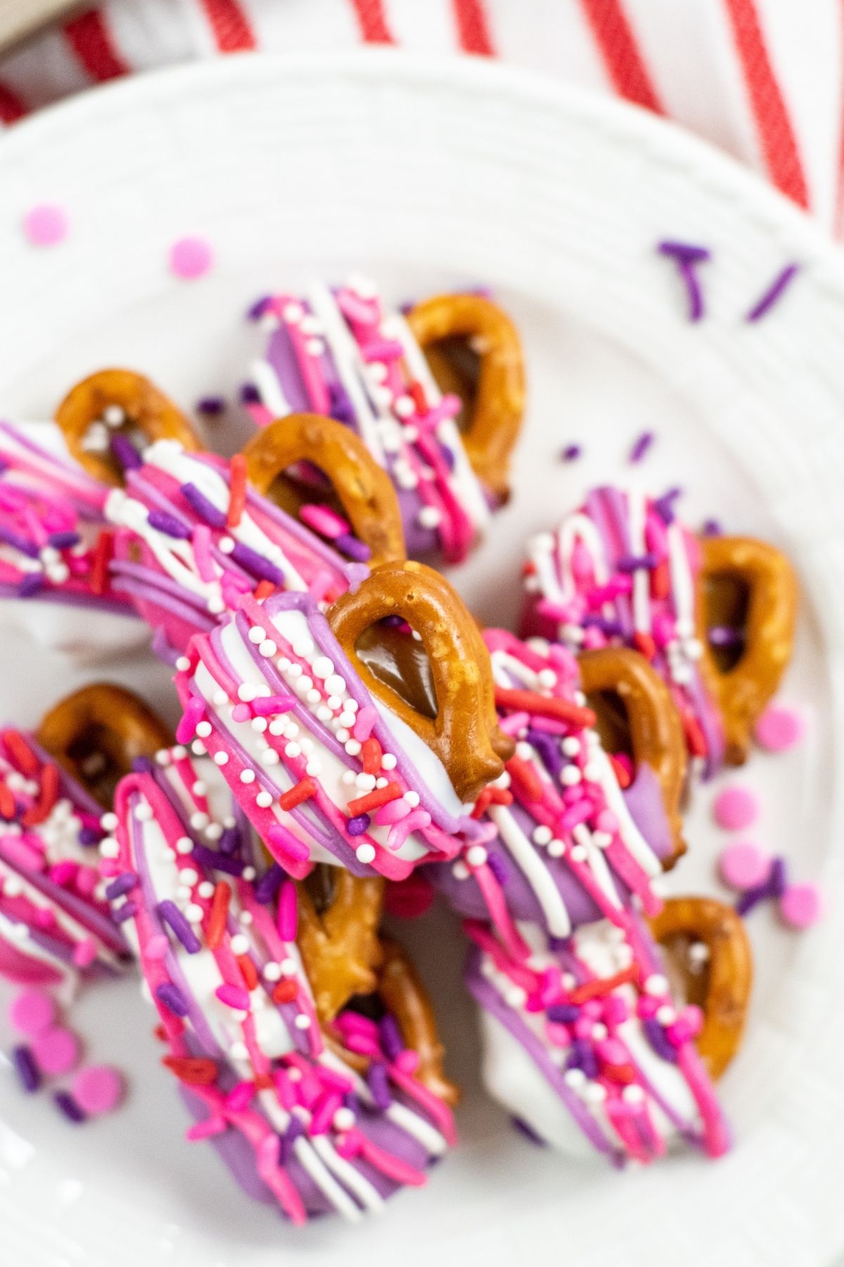 small pretzels with caramel and white chocolate with purple and pink drizzled chocolate and sprinkles