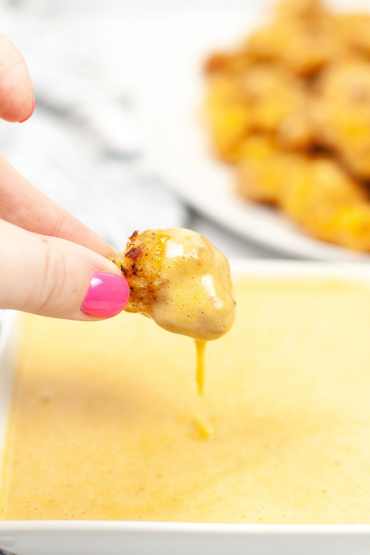 chicken nugget being dipped into yellow chick-fil-a sauce
