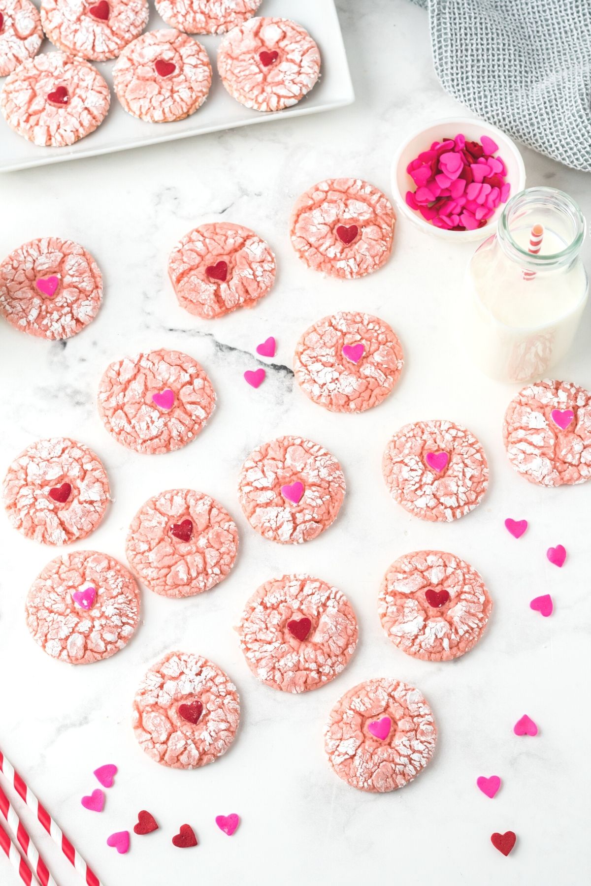 pink crinkle cookies on counter with red and pink sprinkles and red and white straws