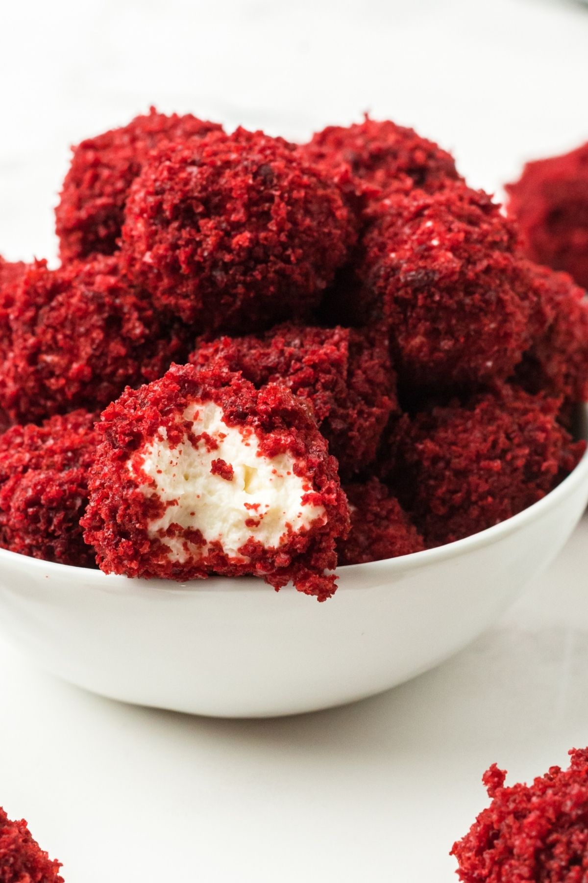 crumbly red velvet balls with cheesecake center in a white bowl