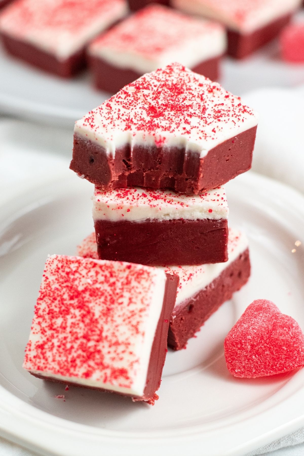 red fudge with white tops and red sprinkles stacked on top of each other