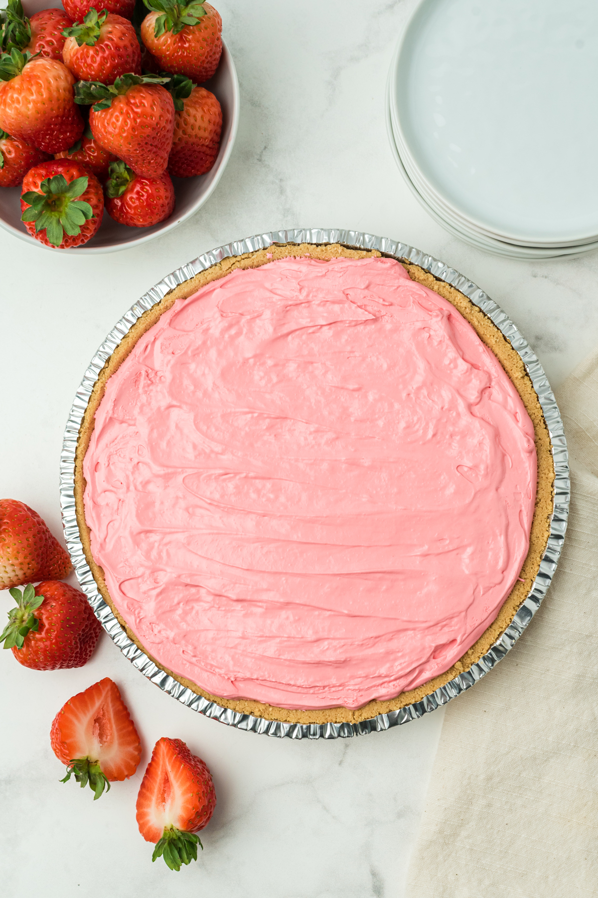 A whole Kool Aid Pie on a white counter with strawberries on the side.