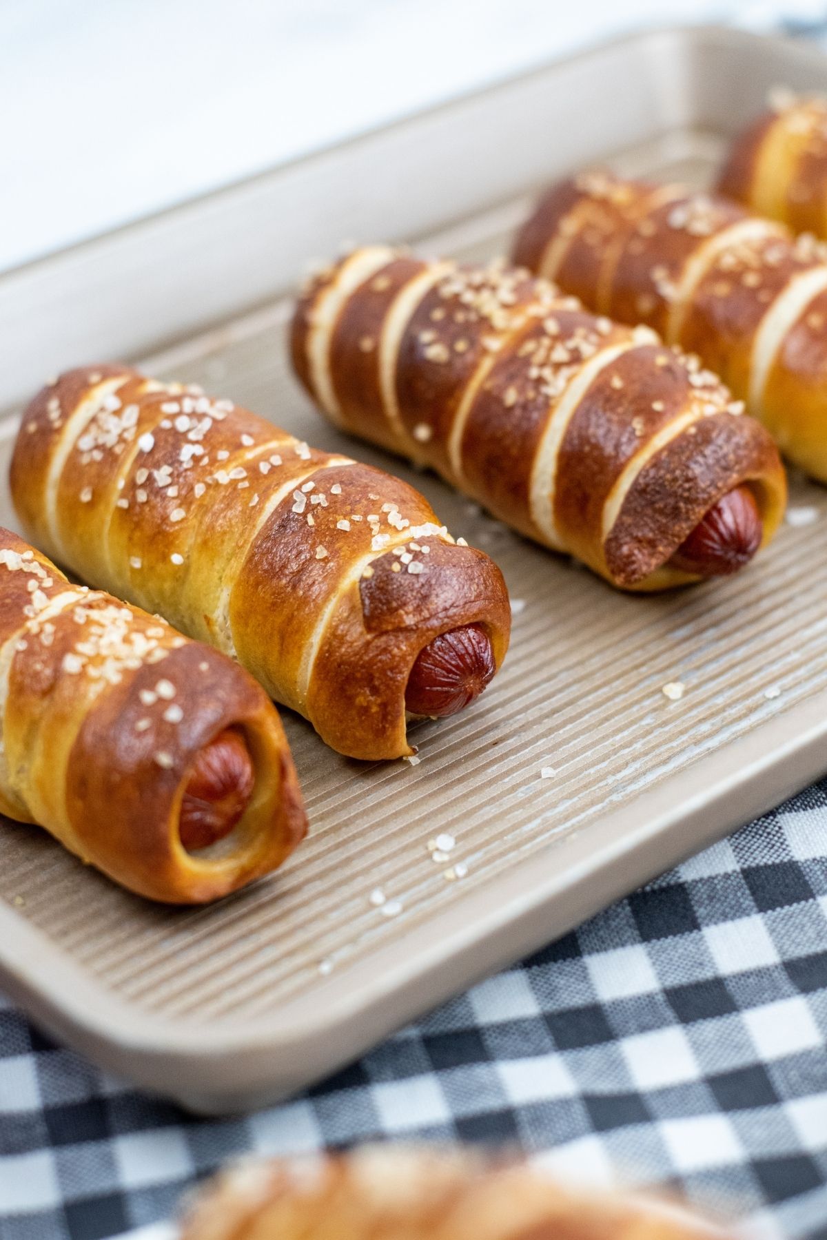 hot dogs wrapped in baked pretzels on baking pan