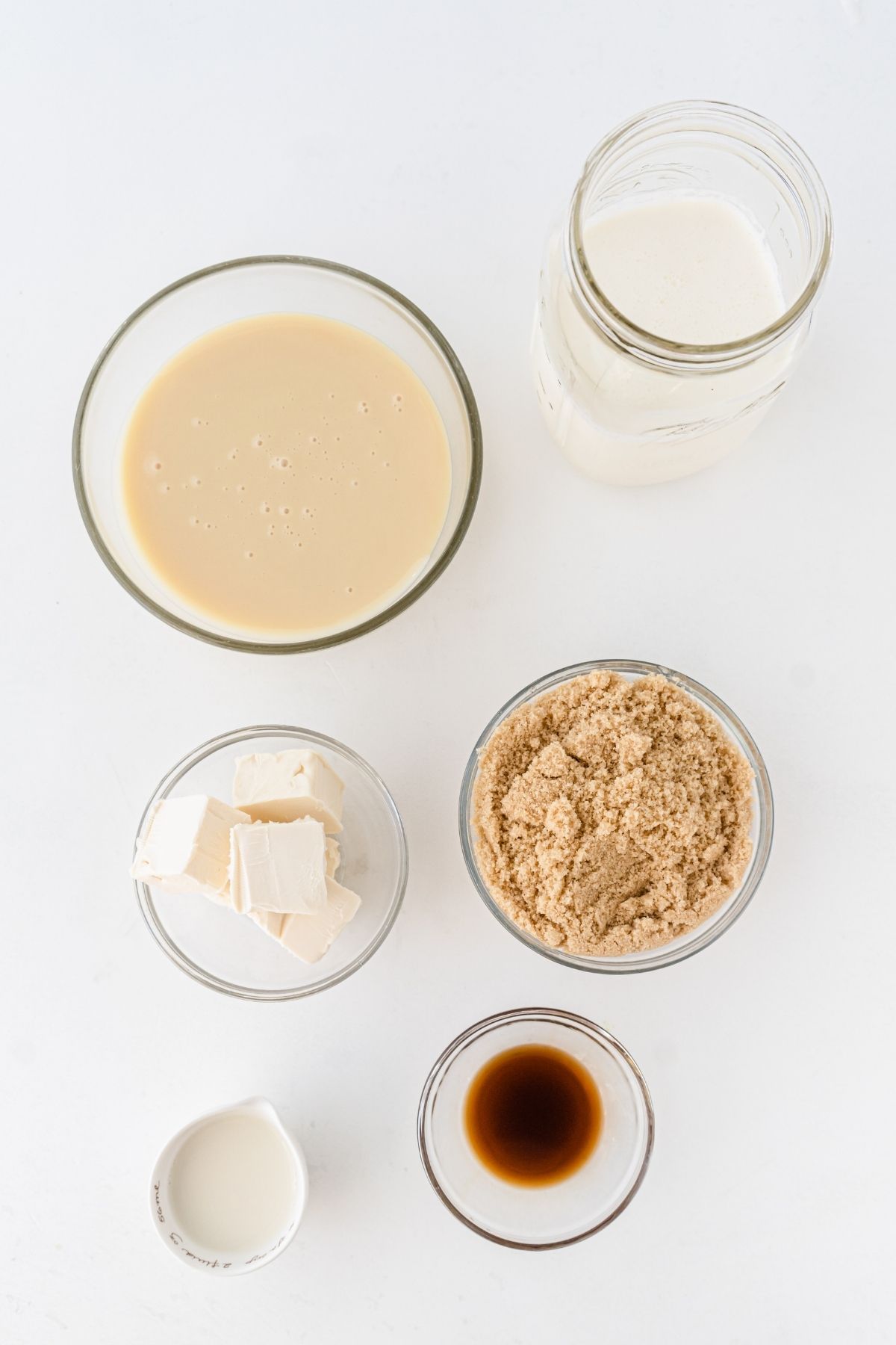 ingredients on white counter: sweetened condensed milk, whipping cream, vanilla, brown sugar, heavy cream, butter