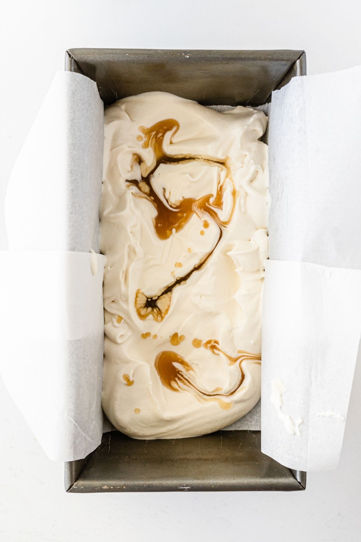 white ice cream with butterscotch drizzled on top in a loaf pan