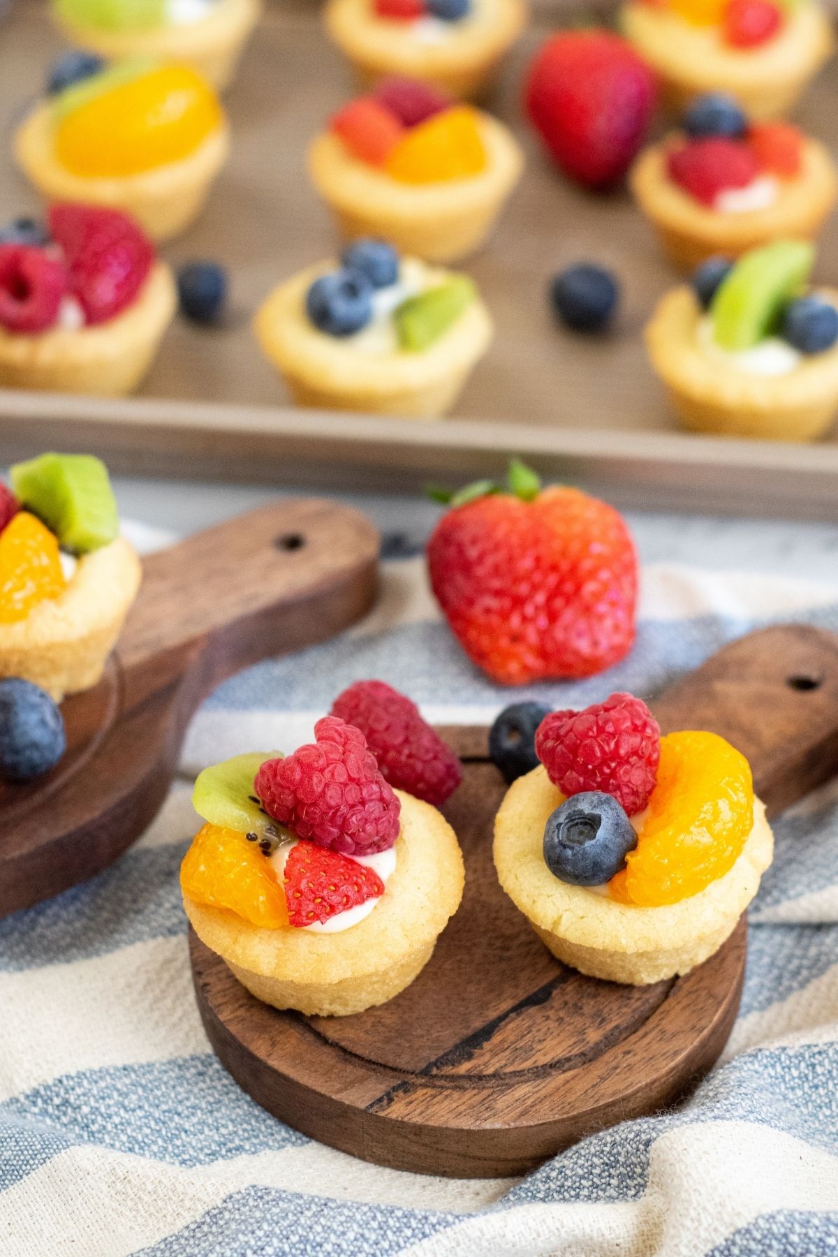 cookie cups with fruit on top on wooden cutting board