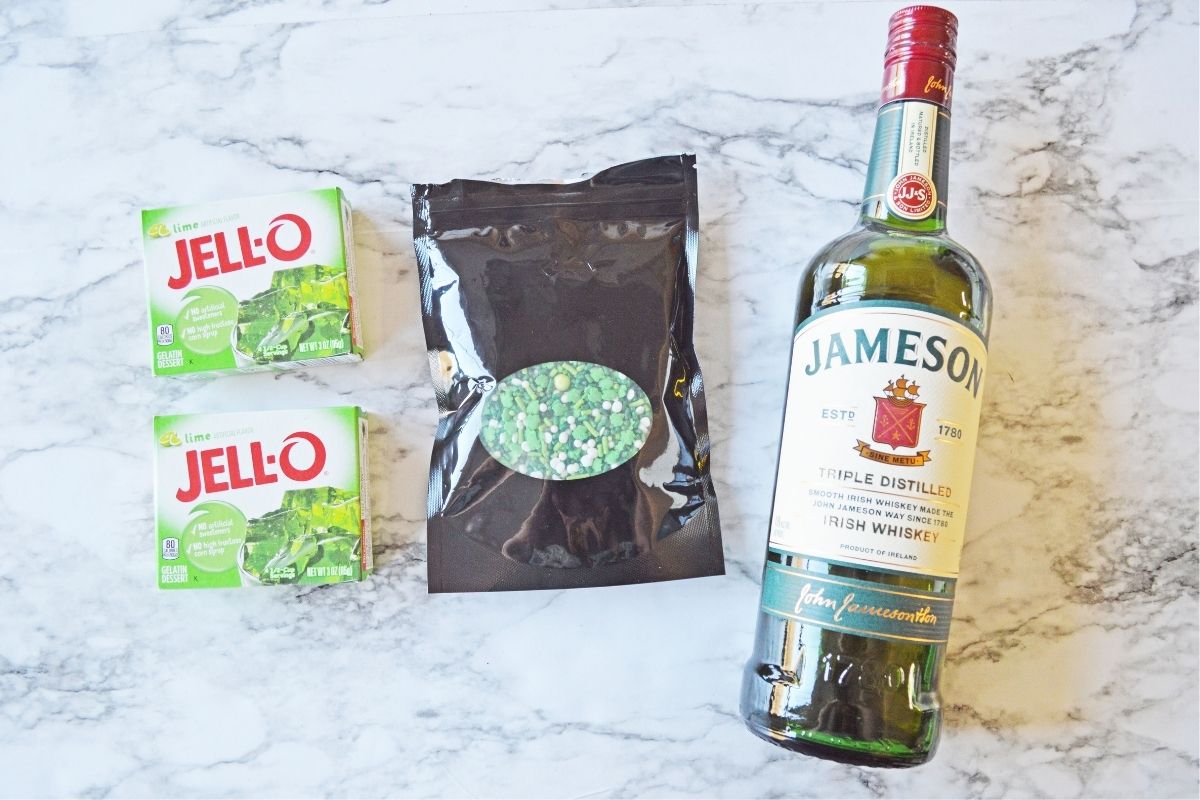 two boxes lime jello, green sprinkles, and Jameson whiskey on white counter