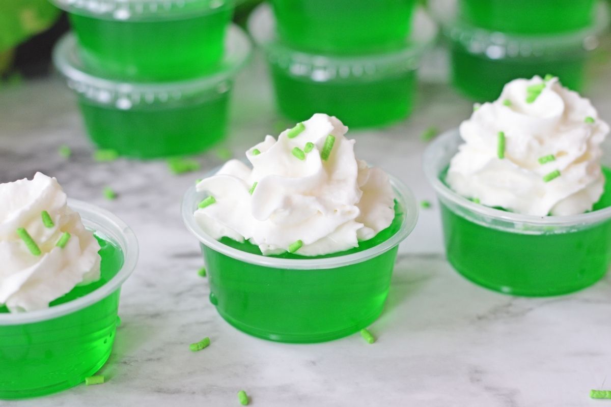green jello in shot cups with whipped cream