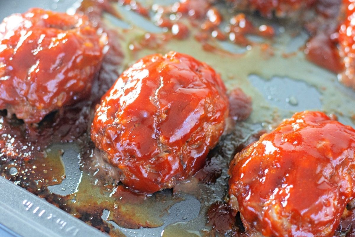 baked meatloafs on baking sheet with bright red glaze on top