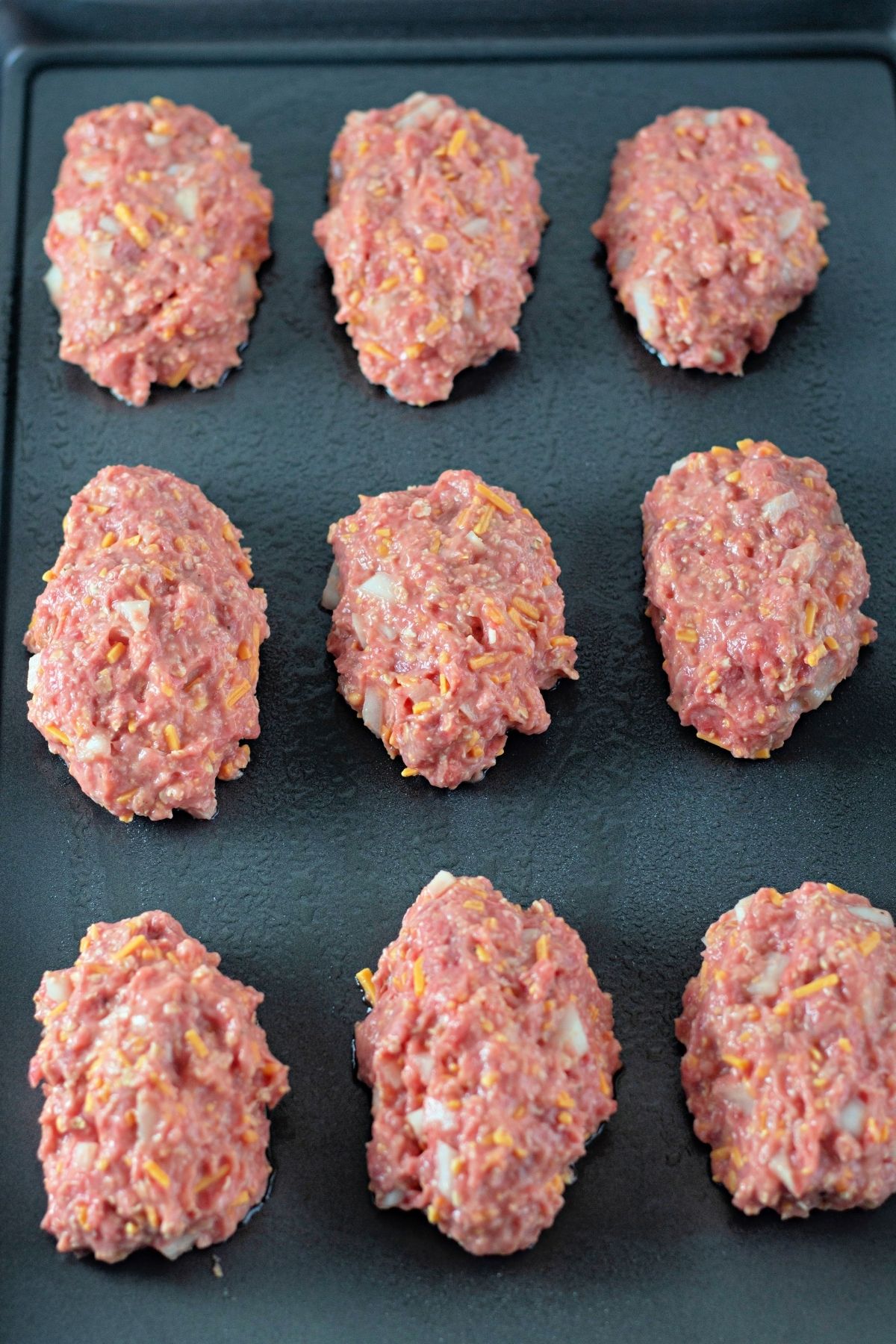 9 raw mini meatloafs on a baking sheet