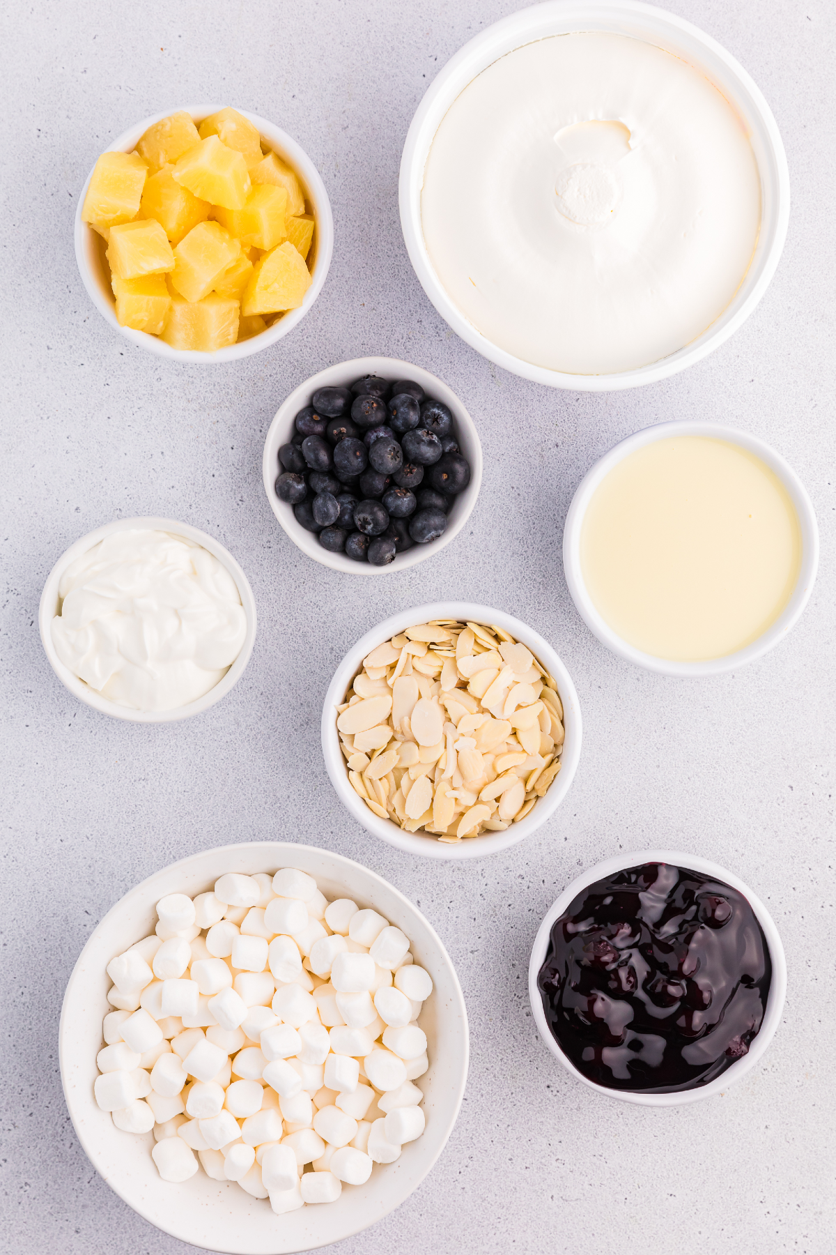 Ingredients for Blueberry Fluff Salad: pineapple, Cool Whip, blueberries, almonds, mini marshmallows, pie filling, sweetened condensed milk and sour cream