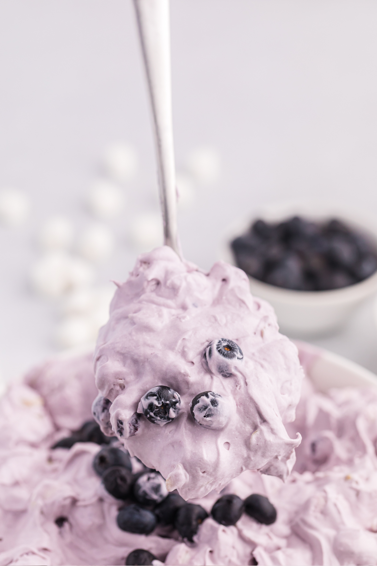 A spoonful of Blueberry Fluff Salad with fresh blueberries