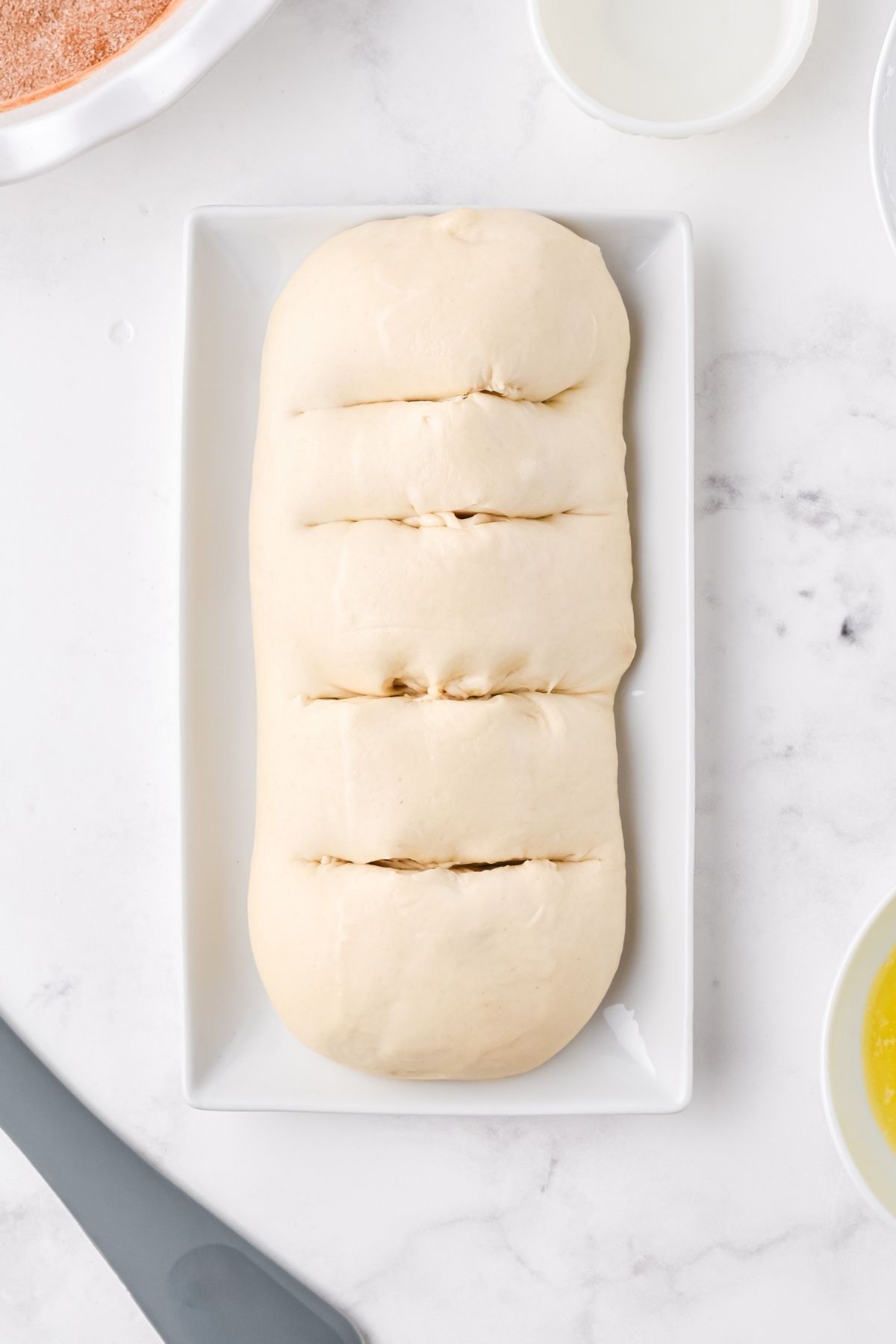 loaf of raw dough with four slits on top