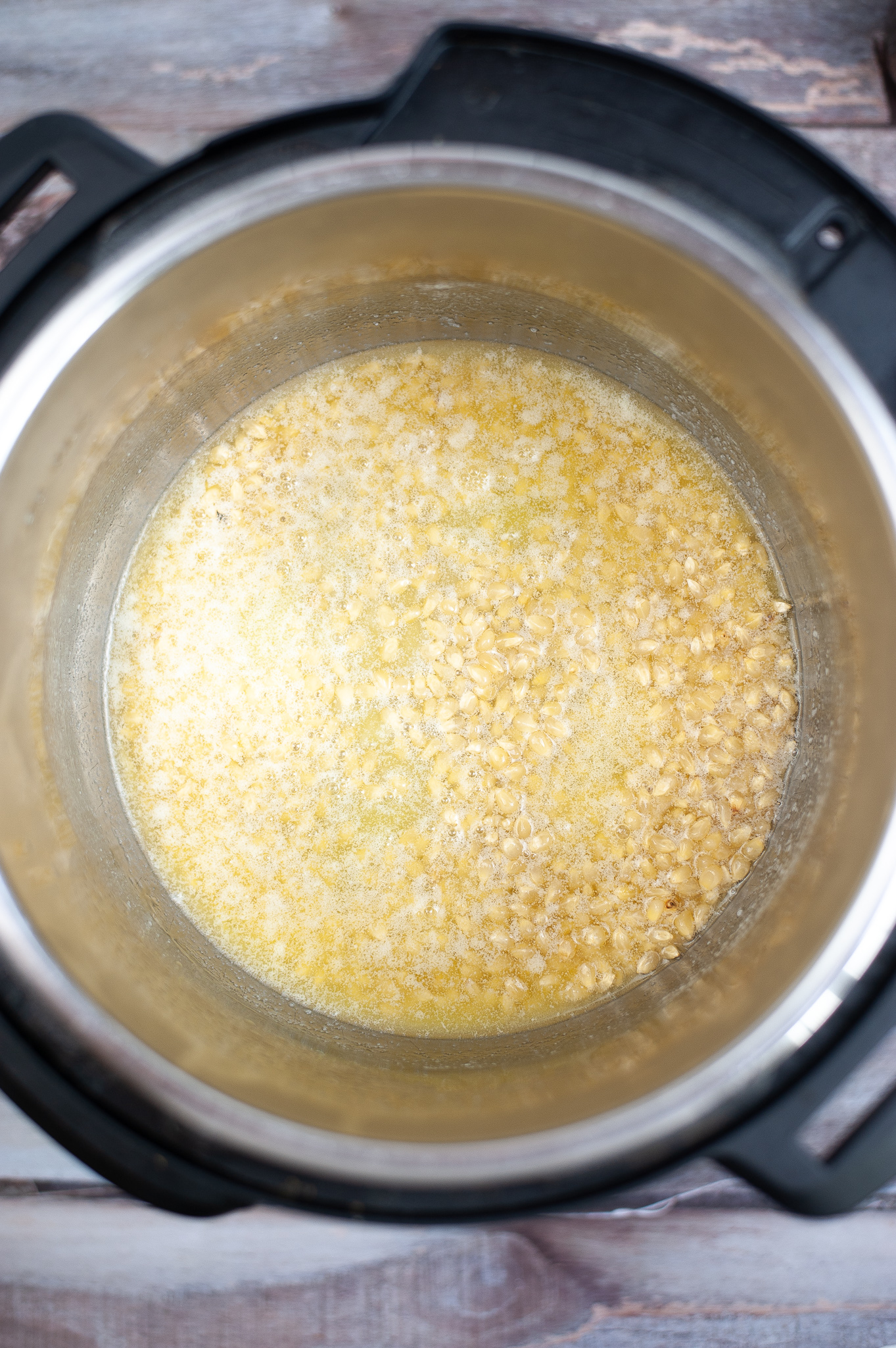 Instant pot with melted butter with popcorn kernels at the bottom.
