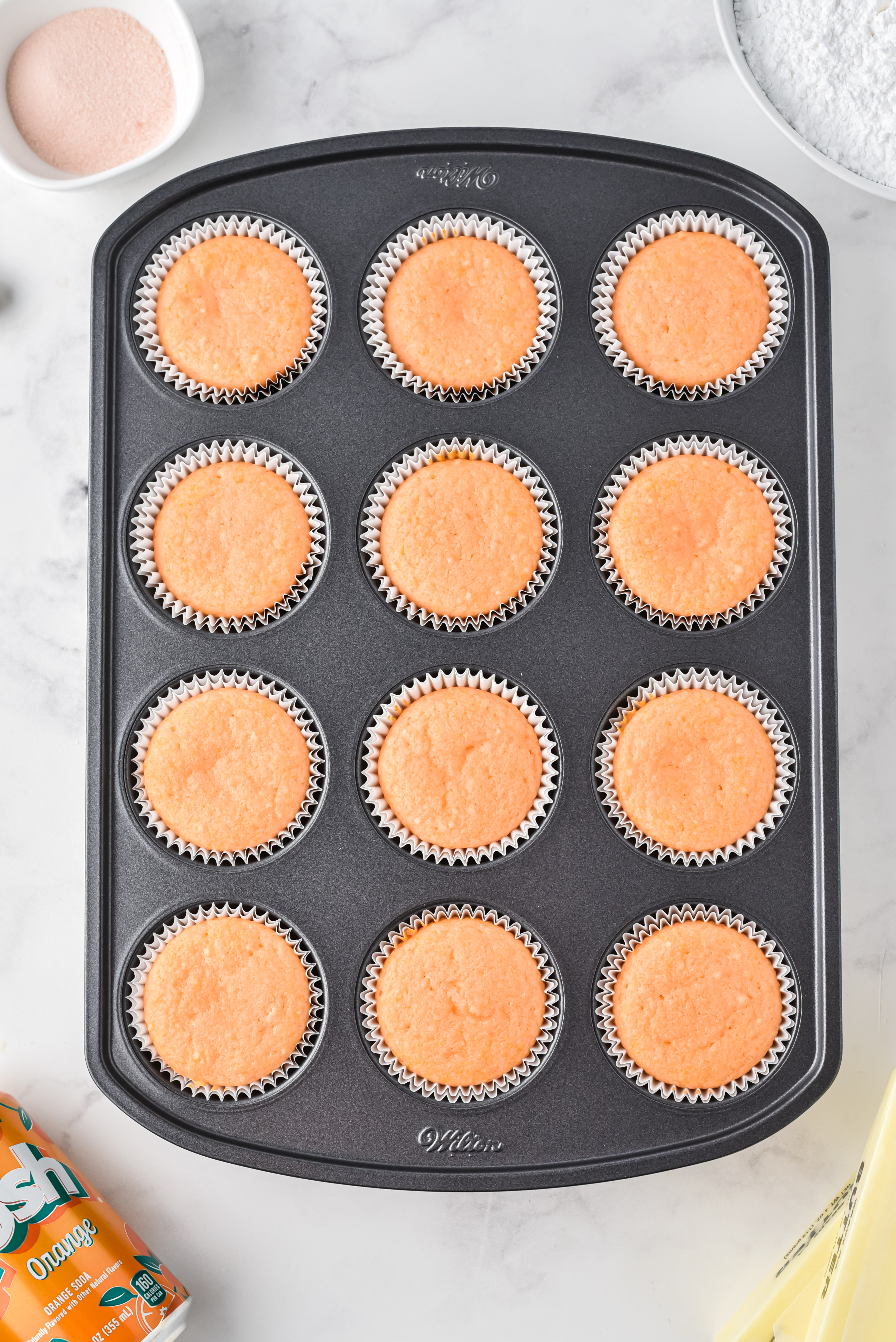 12 cake cupcake tray filled with freshly baked cupcakes in white paper liners.