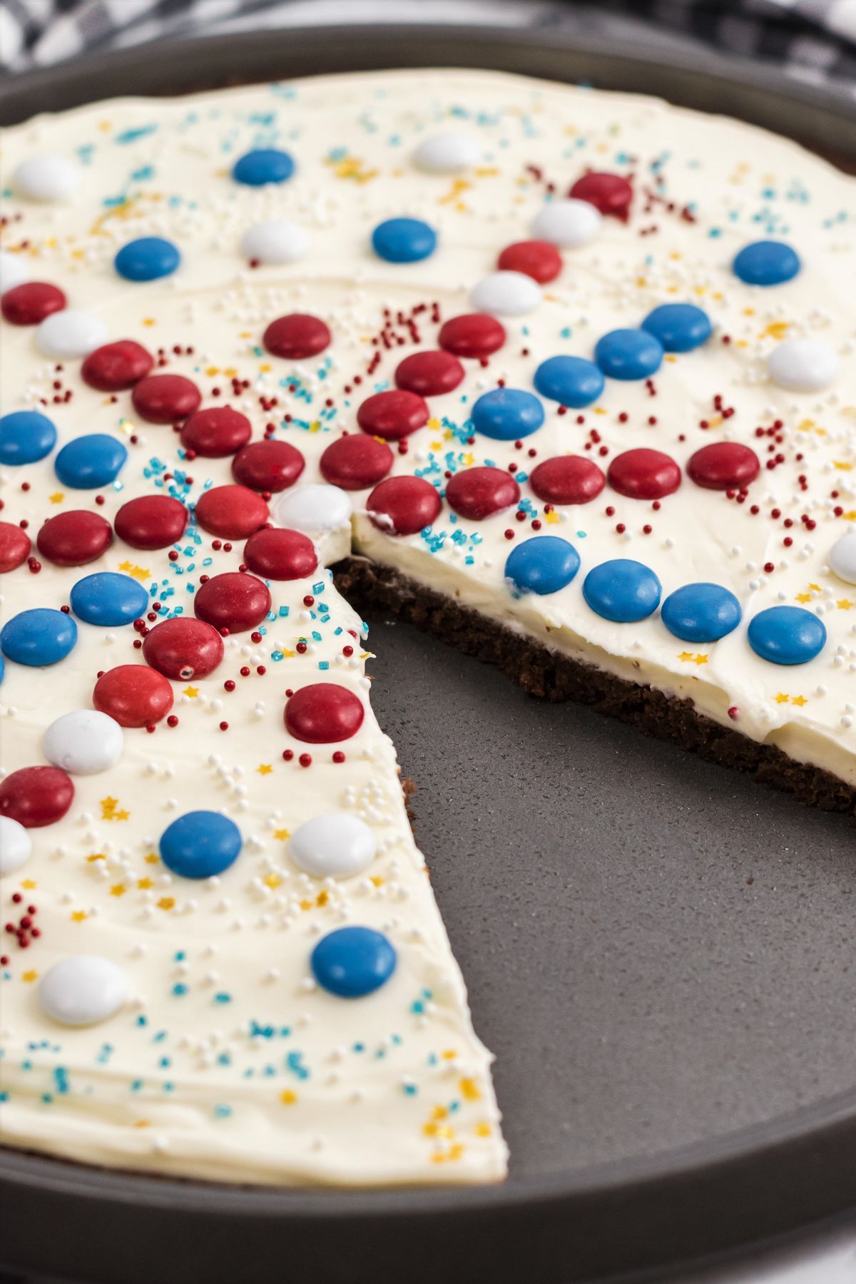 round brownie pizza with white icing and red, white, and blue M&Ms