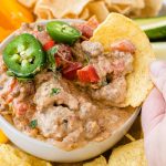 rotel dip in white bowl with jalapeños and chips