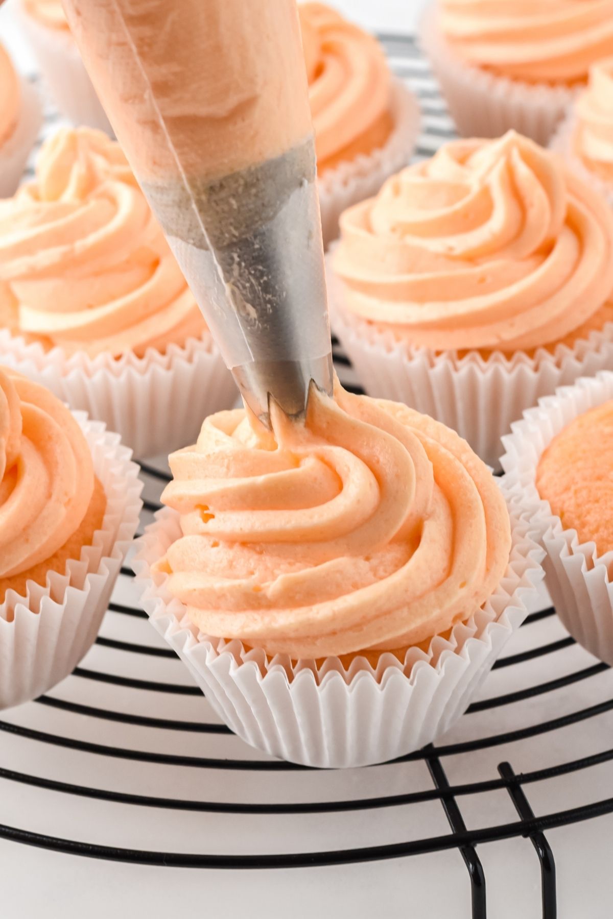 piping bag frosting orange frosting on cupcakes