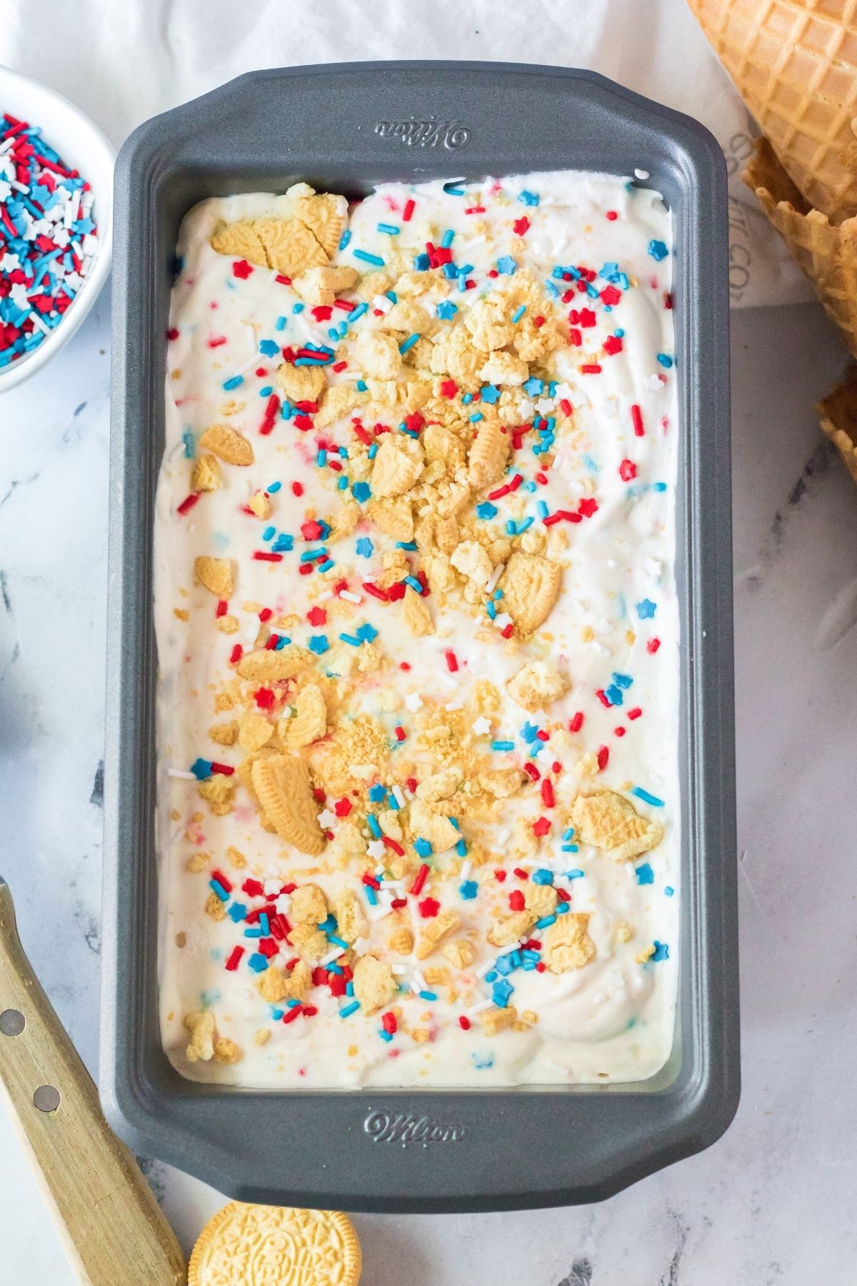 ice cream in a loaf pan with crushed golden Oreos and sprinkles on top