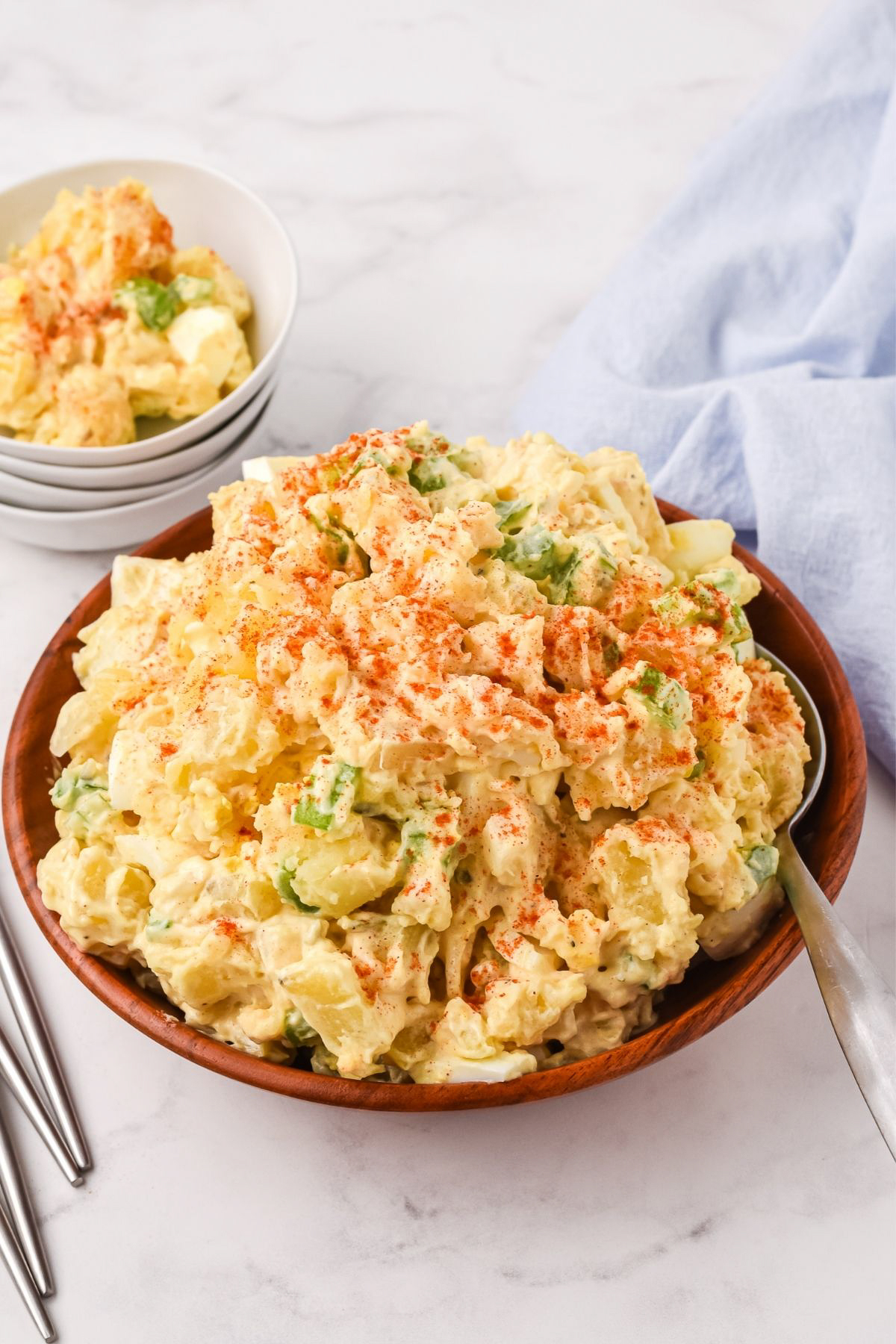heaping pile of potato salad with paprika in wooden serving bowl
