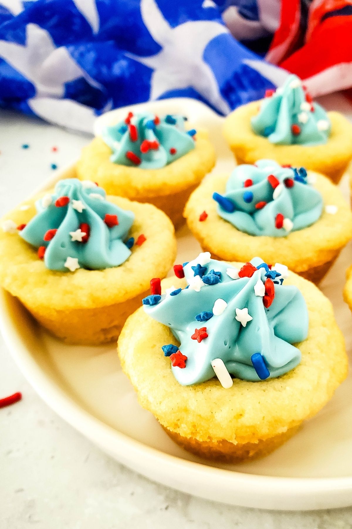 sugar cookie cups with light blue frosting and red, white, and blue sprinkles