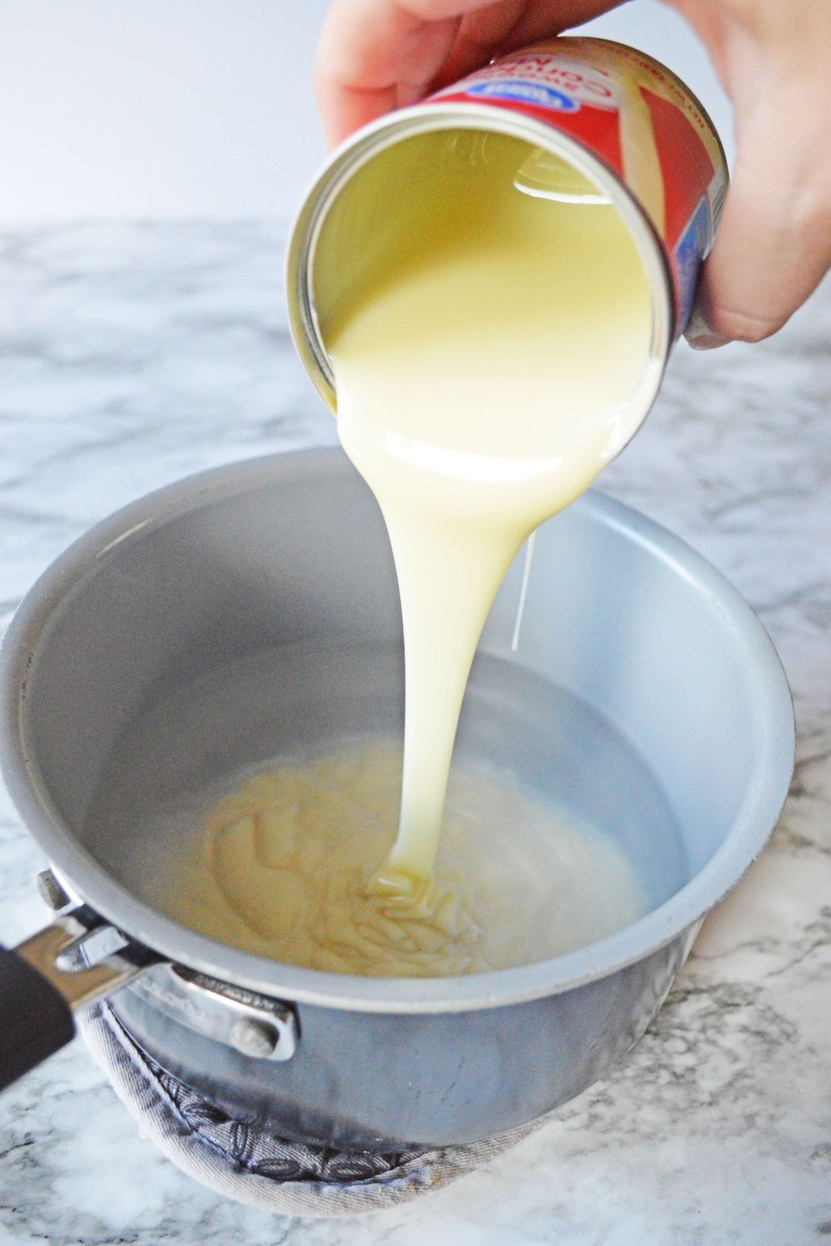 pouring can of condensed milk into sauce pan
