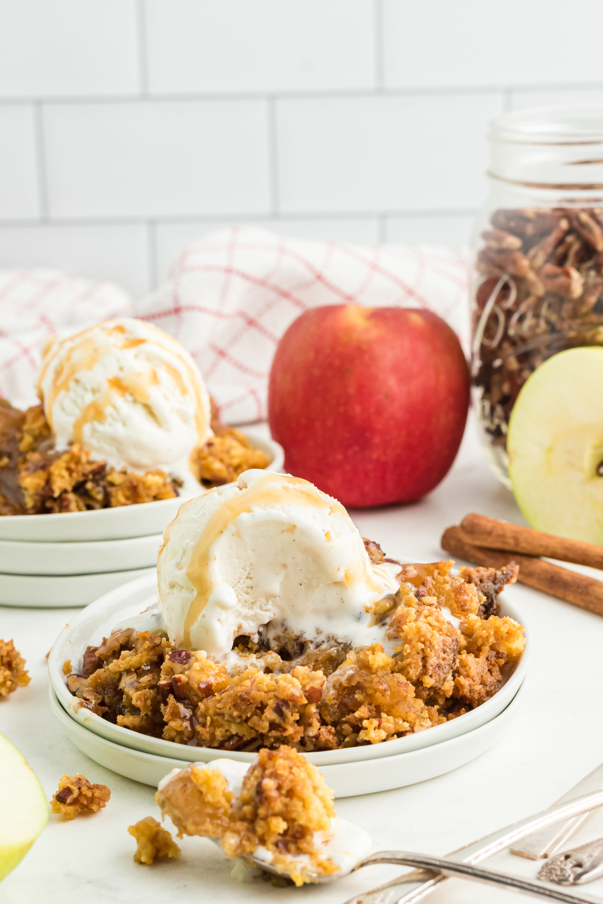 An upclose photo of Apple Dump Cake on a white plate with ingredients on background
