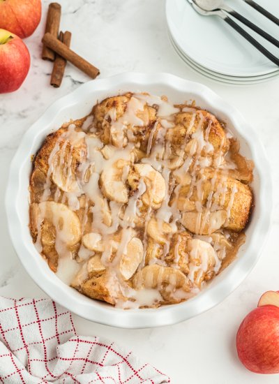 Top view of a white pie dish filled with Cinnamon Roll Apple Bake with drizzled frosting on top.