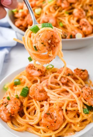 fork twirling bang bang shrimp with pasta over a bowl
