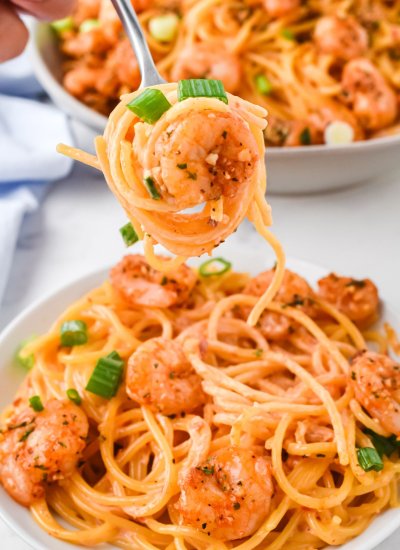 fork twirling bang bang shrimp with pasta over a bowl