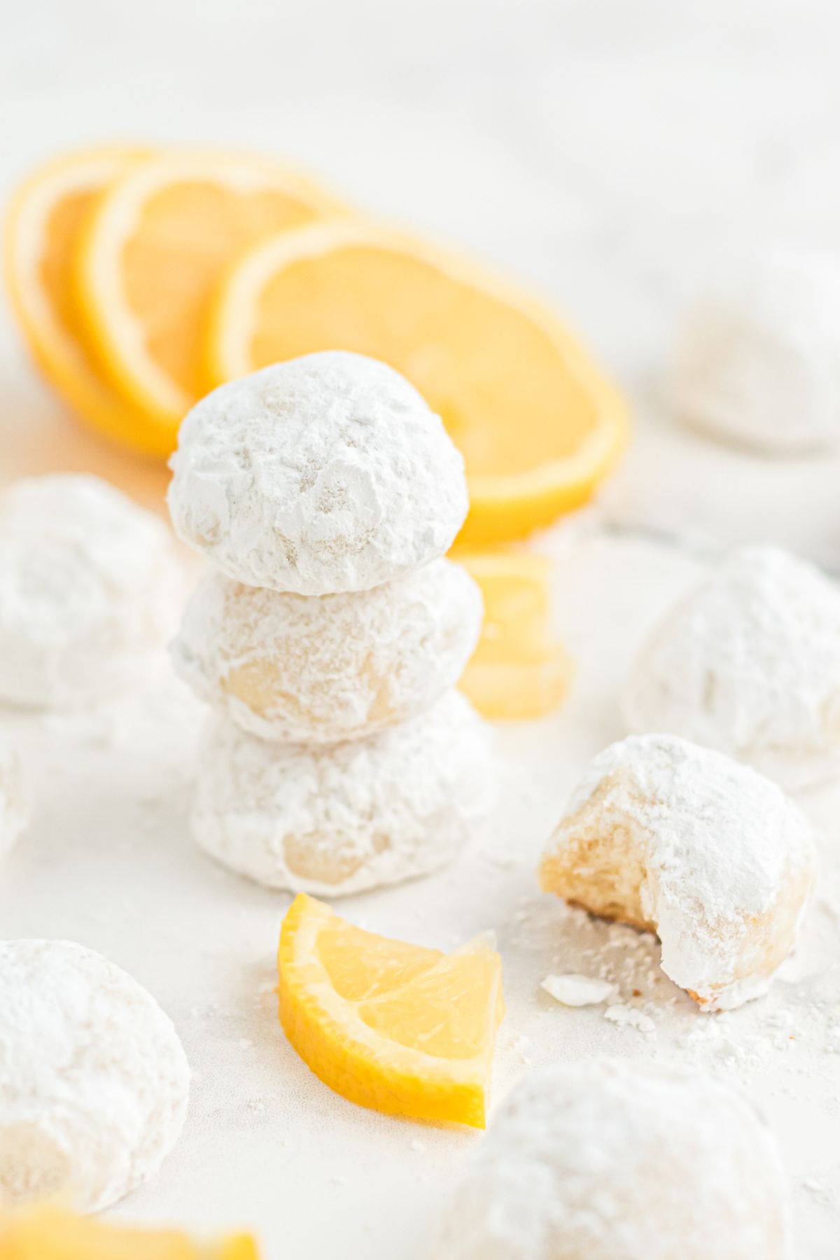 round lemon cooler cookies stacked with sliced lemons on the side