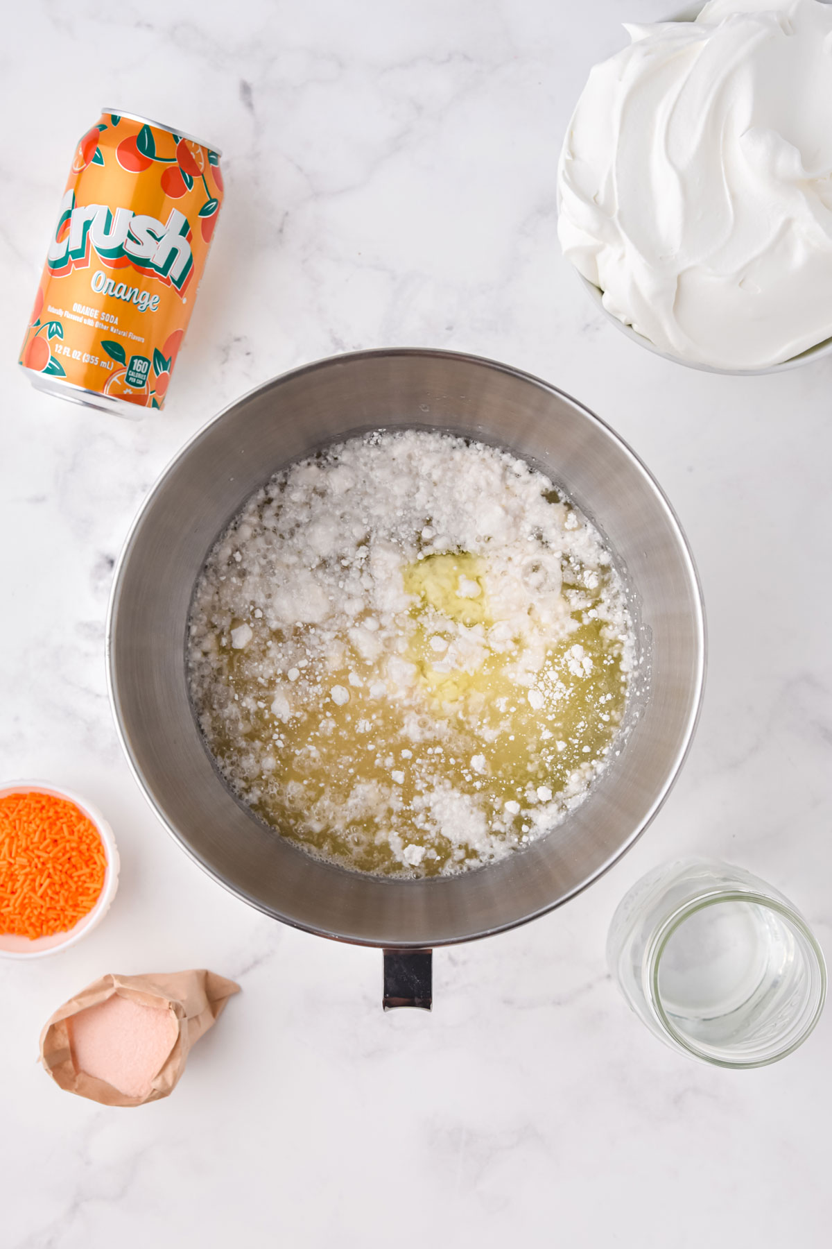 Proces of making an Orange Crush Poke Cake is to prepare the cake batter by mixing the cake mix, oil, egg whites and water.