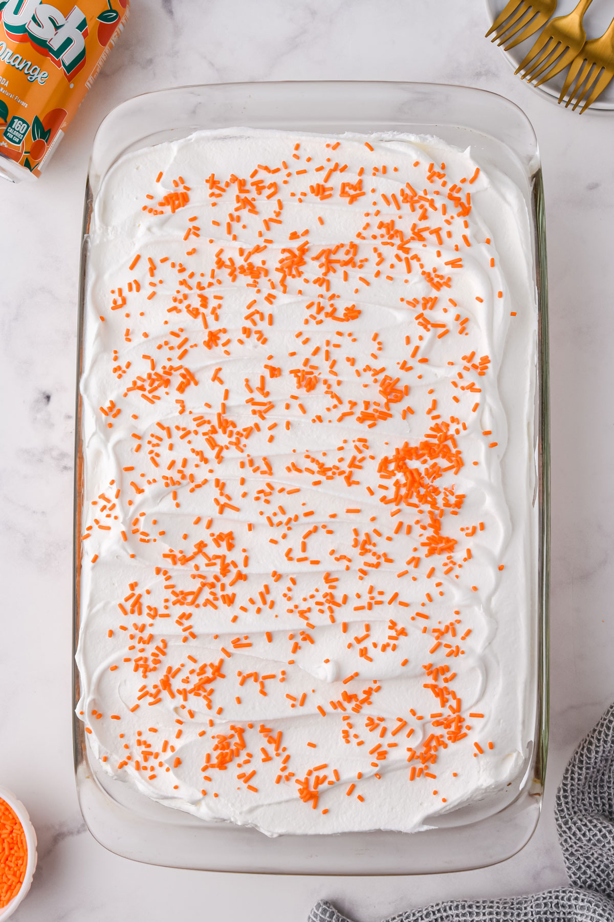 Adding the filling of Orange Crush Poke Cake and putting orange sprinkles. 