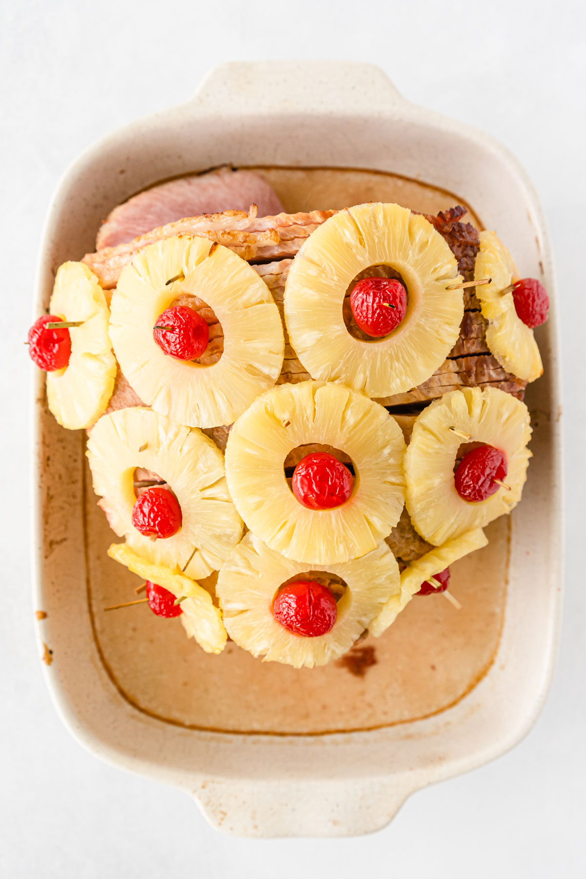 The process of Pineapple Ham with Brown Sugar Marinade is to add cherries and pineapple on ham.