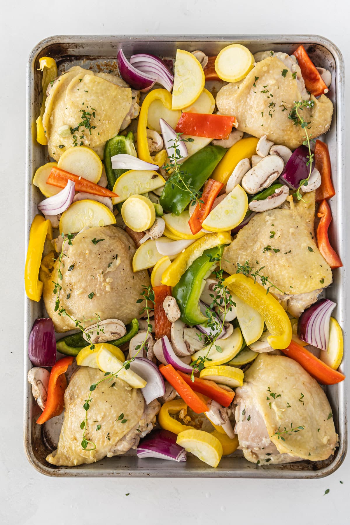 A tray of Sheet pan Chicken Thighs with herbs and vegetables