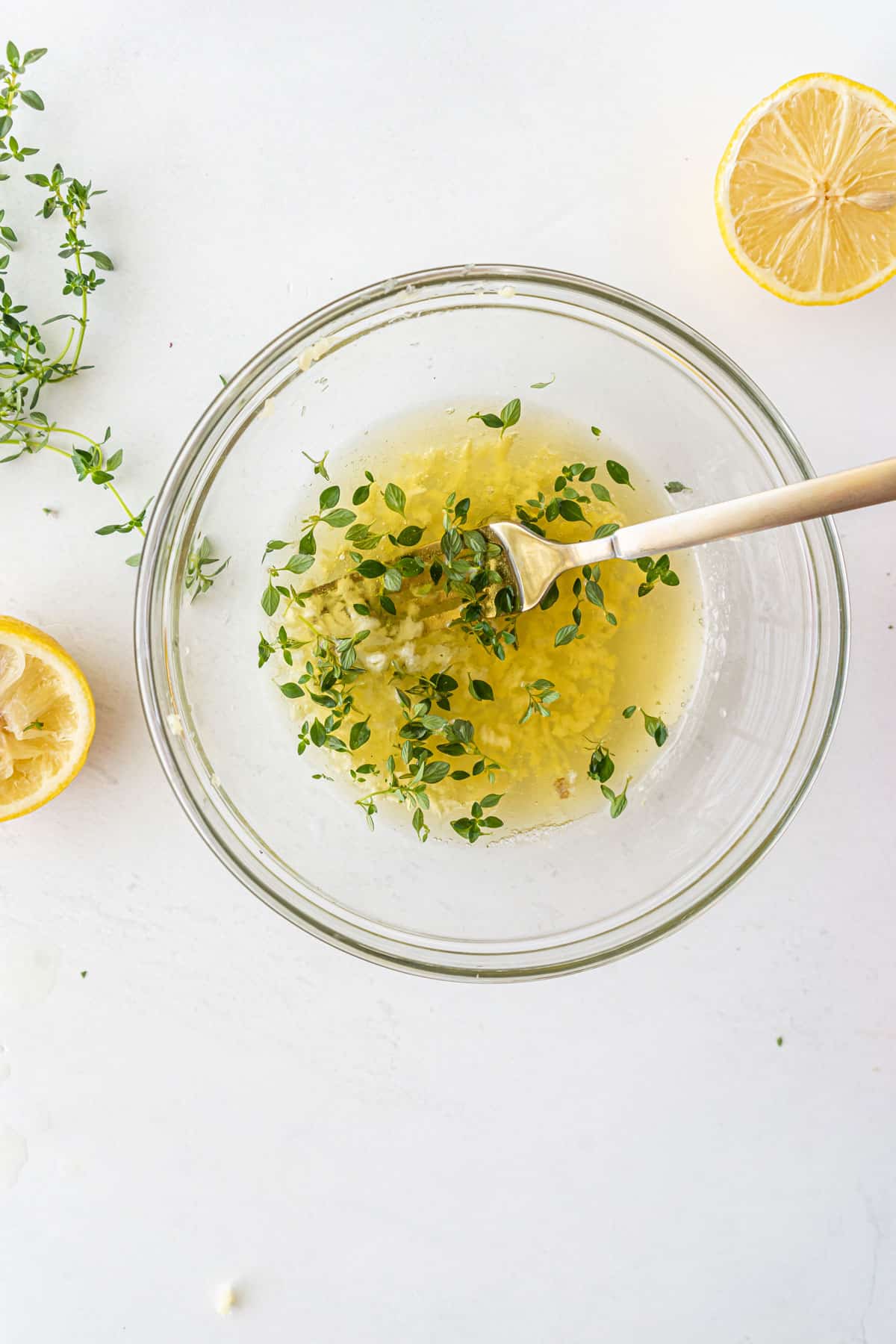 Combinging oil, garlic, lemon juice and thyme in a bowl for Sheet pan Chicken Thighs recipe