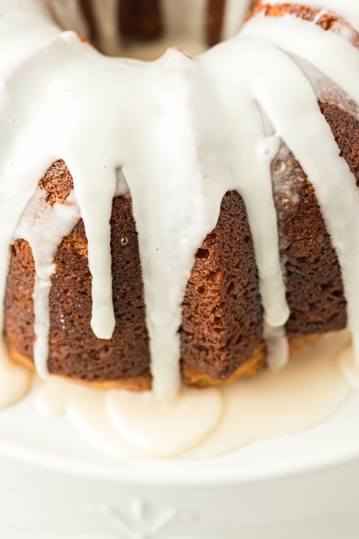close up of top and side of bundt cake with icing dripping down the side