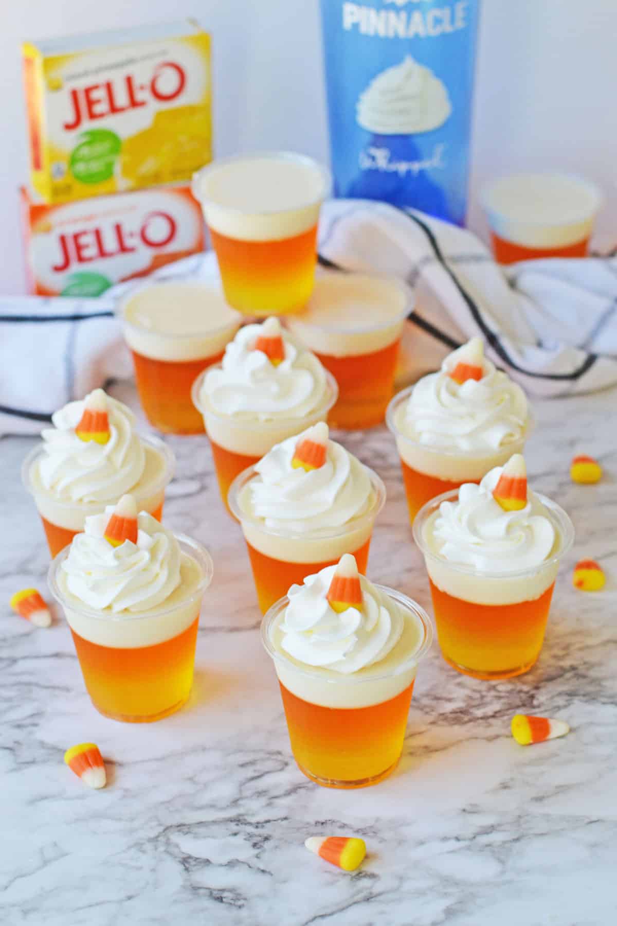 Candy Corn Jello Shots on a marble counter with ingredients on the side