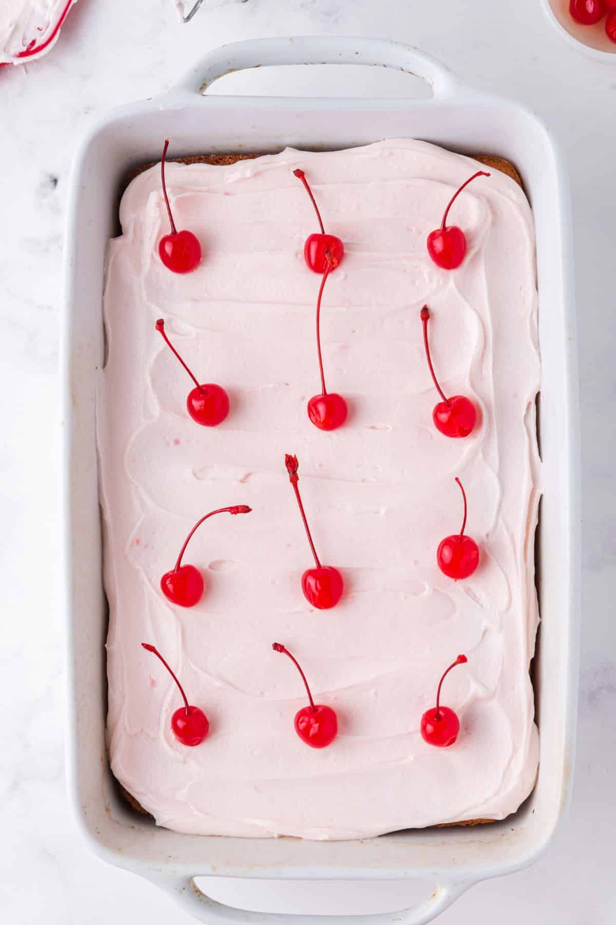 top down of frosted cake with cherries in rows on top