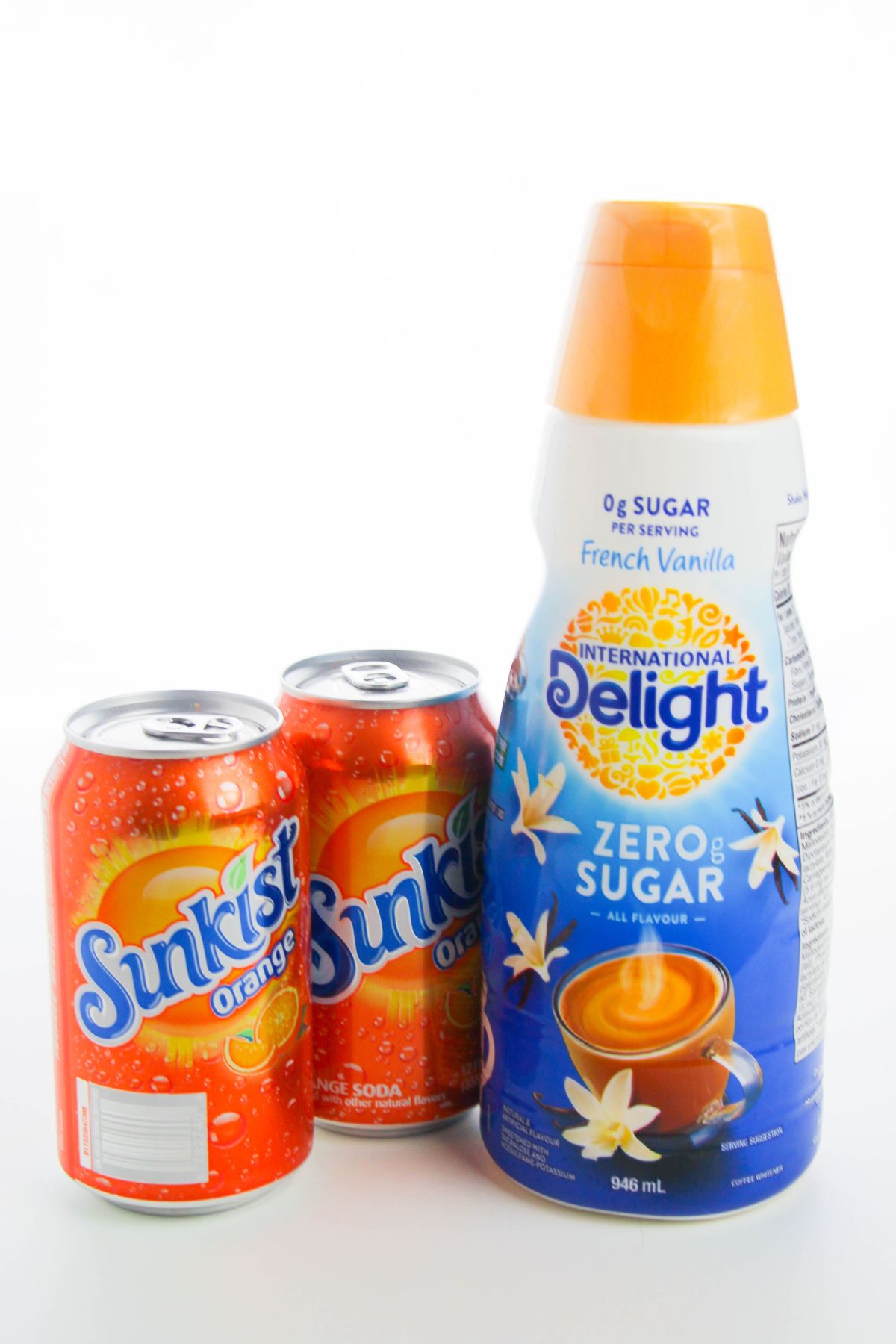 two Sunkist soda cans and a container of French Vanilla creamer