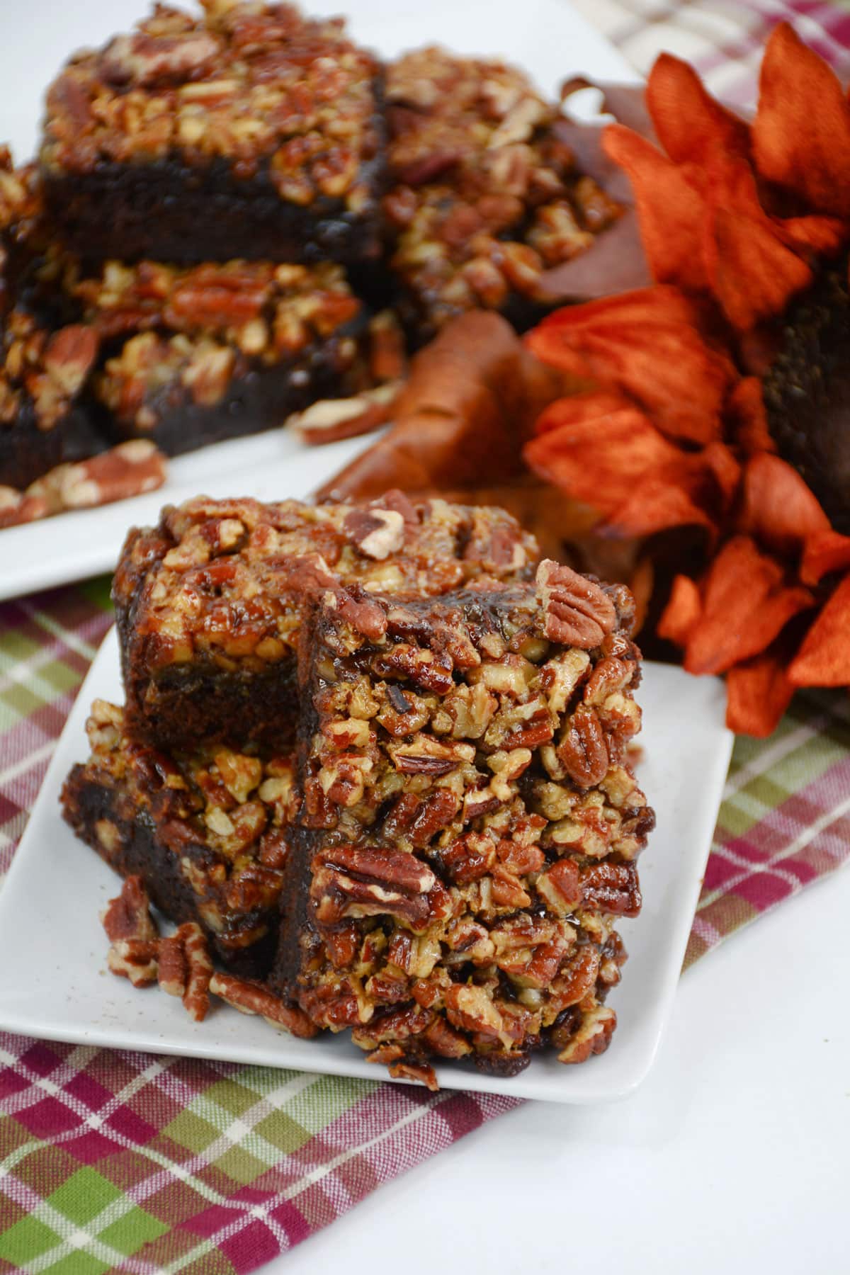 brownie squares stacked on plate with fall decor in the background