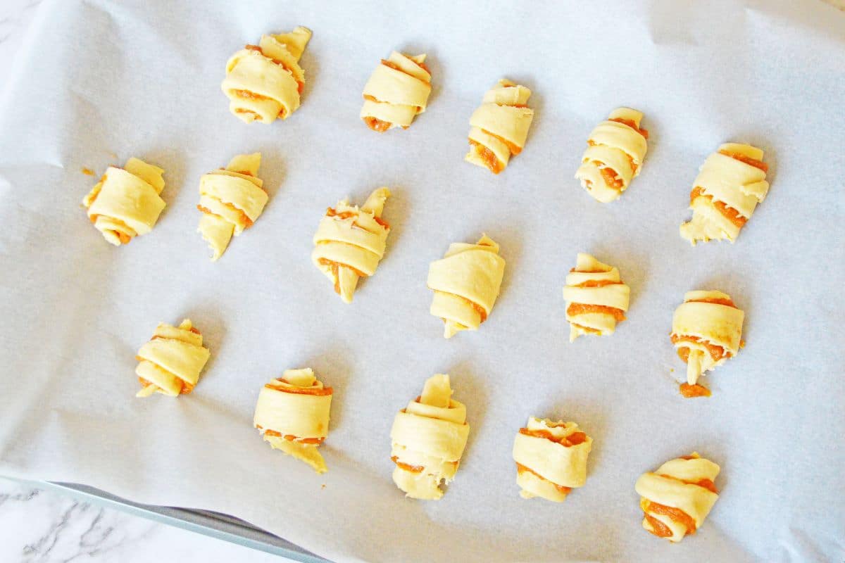 raw crescent rolls with pumpkin filling on parchment paper