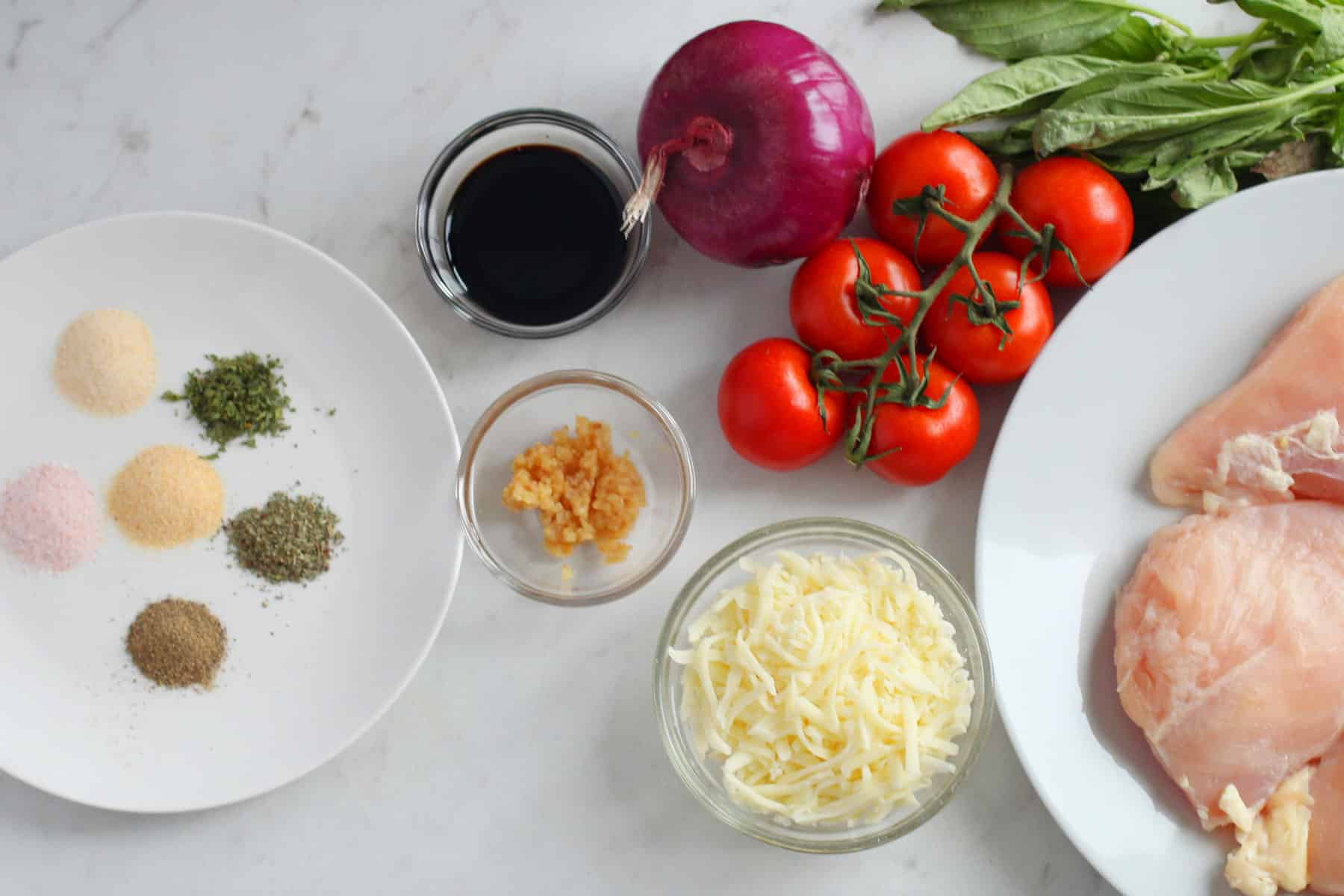 Ingredients for Bruschetta Chicken recipe includes tomatoes, basil, chicken, garlic, mozarella cheese, balsamic vinegar, salt, avocado oil, pepper, and onion powder